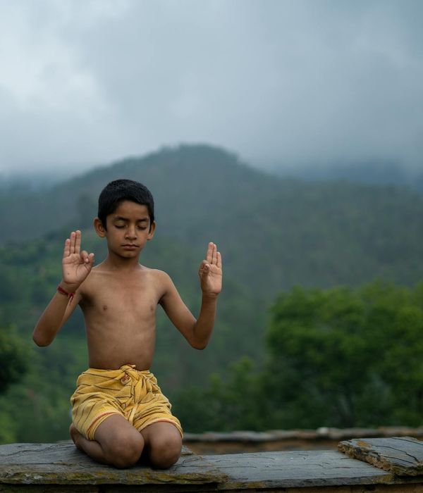 Person meditating peacefully outdoors with nature background.